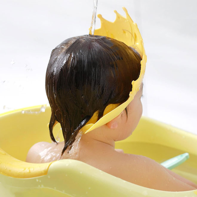 A child wearing a shampoo guard having their hair washed
