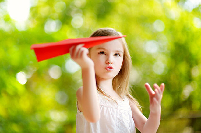 Little girl flying a paper plane