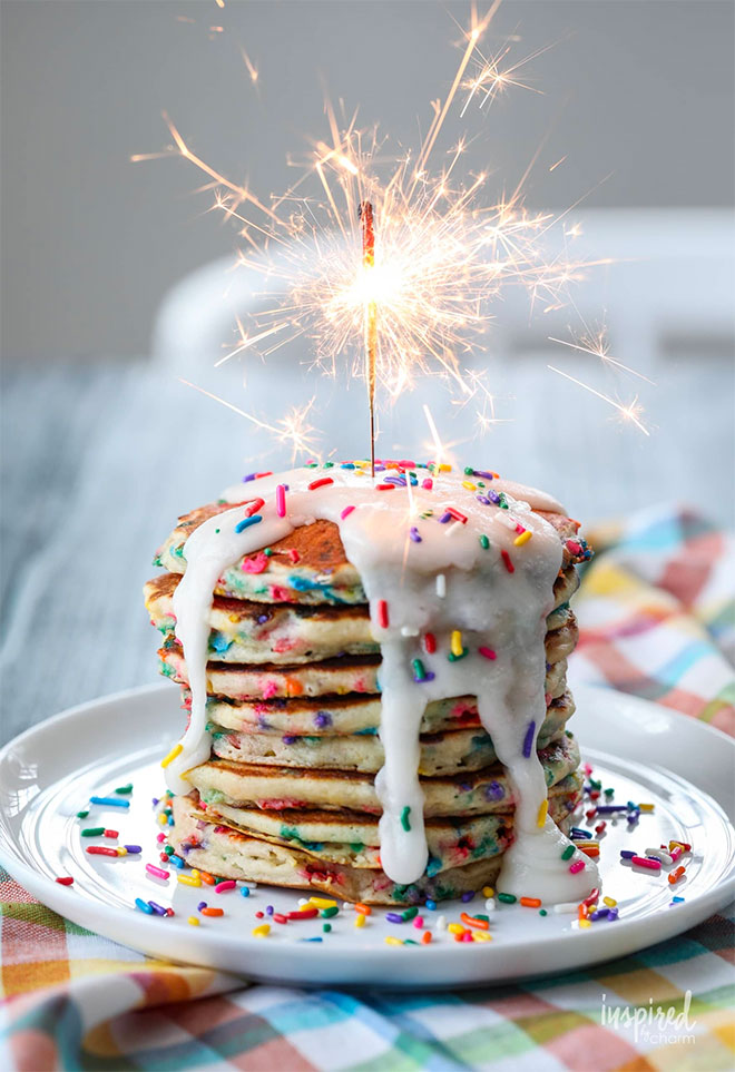 A stack of funfetti pancakes with a lit sparkler