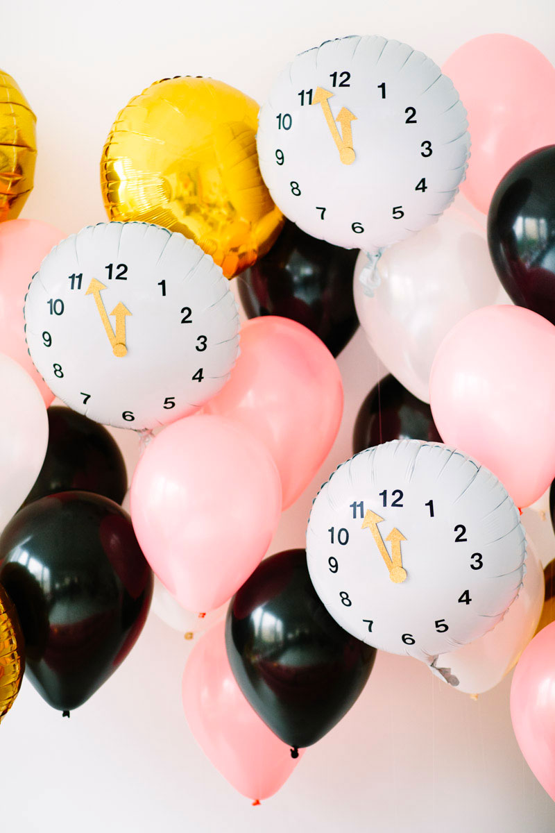 Bunch of balloons, gold, black and white with clock faces pointing to 12 oclock