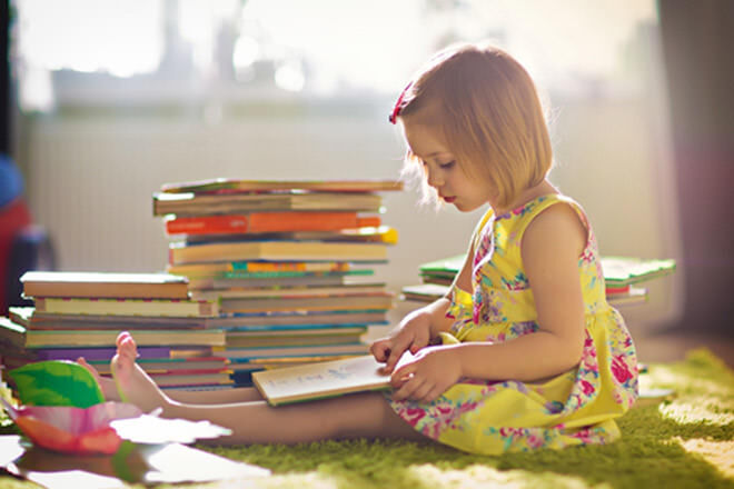 Little girl next to a pile of children's books