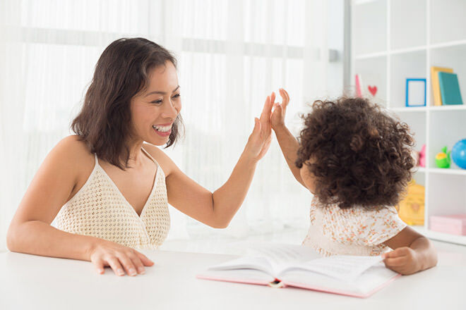 Mother high-fiving daughter reading