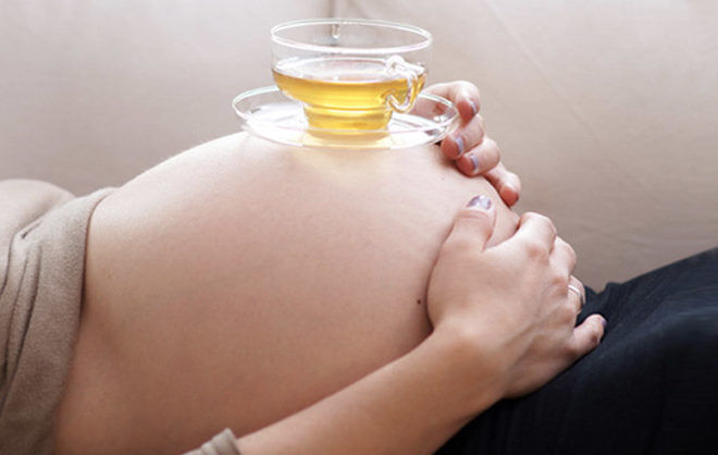 Cup of tea on pregnant belly STK