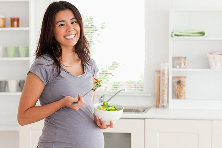 Happy pregnant women eating salad