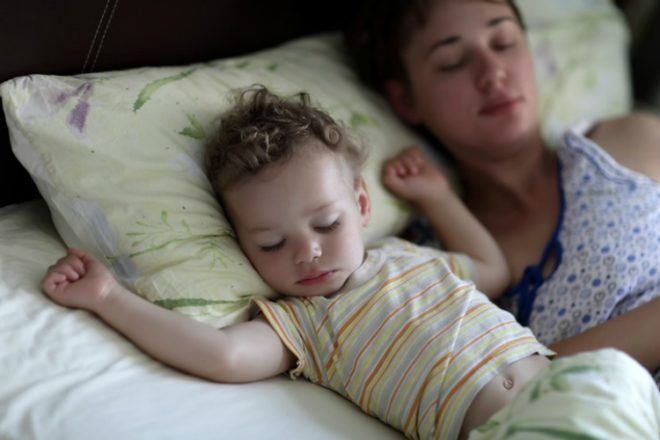 Mother with toddler are sleeping on a bed in the morning