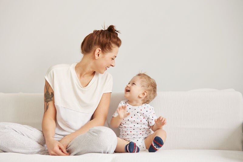 Mother and baby sitting on bed laughing together