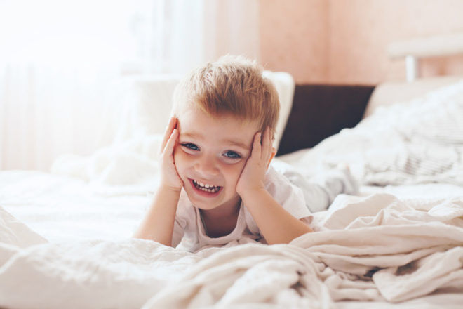happy toddler lying on bed