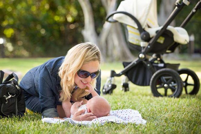 Mum and newborn baby in the park with a pram