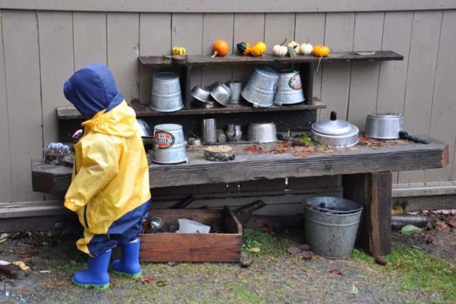 outdoor mud kitchen toddler play wearing gumboots