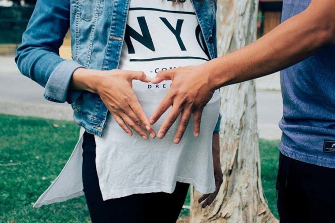 man hand on belly of pregnant woman - preparing for baby