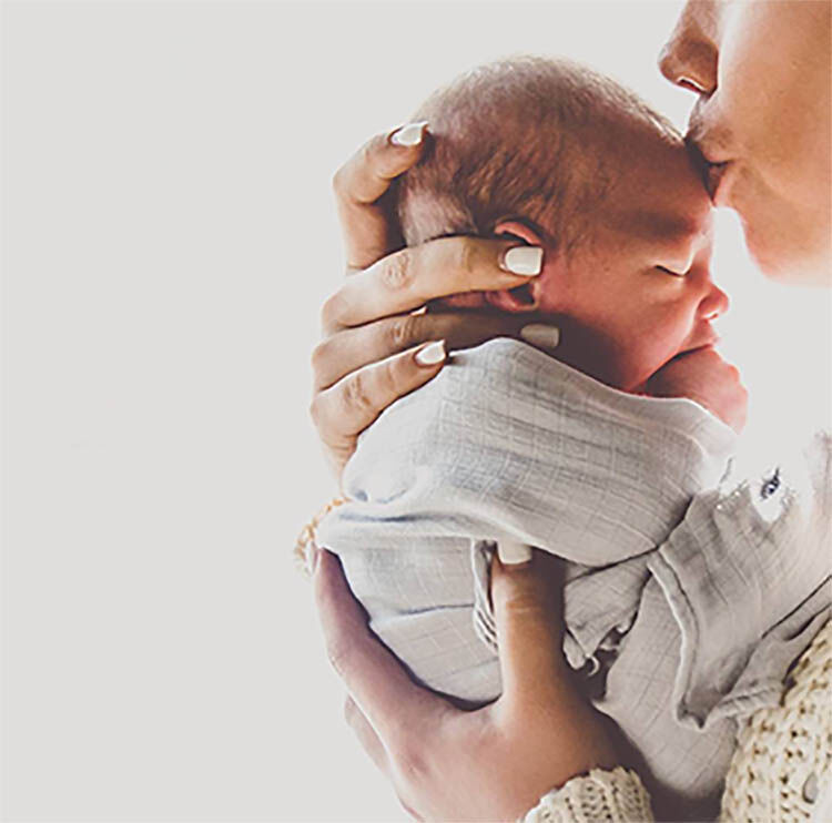 mother kissing newborn