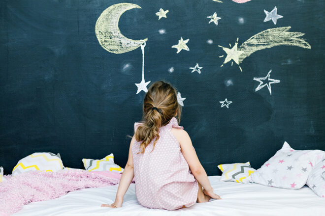 Child in bed looking at wall moon and stars