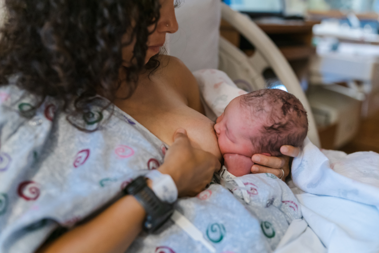 Mother using the football hold to breastfeed a newborn baby