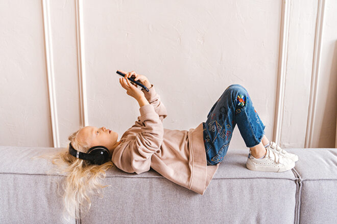 Girl with headphones lying on couch with phone