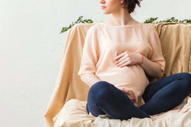 Gestational Diabetes: pregnant mum holding belly in peach top