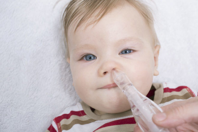 Baby with nasal aspirator unblocking nose 