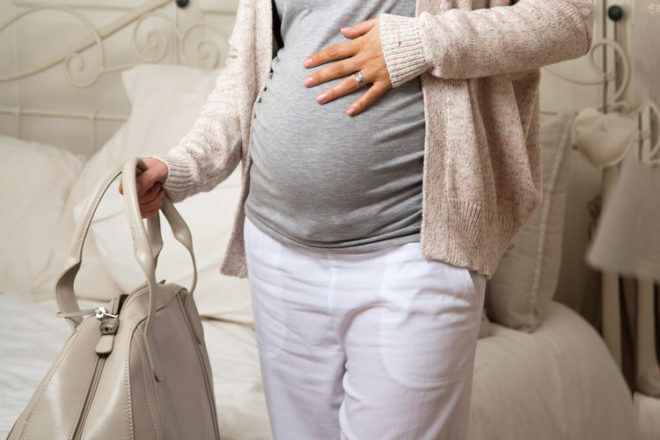 Pregnant women holding hospital bag stk si