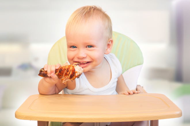 Toddlers eating chicken drumstick with hands