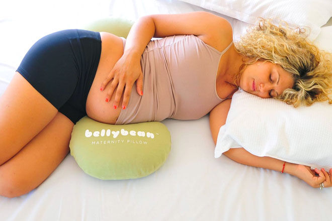 Belly Bean pillow showing a pregnant woman with the pillow placed in the correct position to support her baby belly best. 
