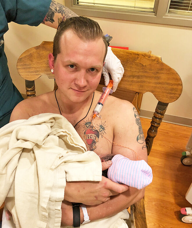 Dad breastfeeding newborn daughter