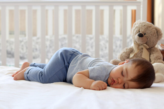 Sleeping toddler on stomach in cot