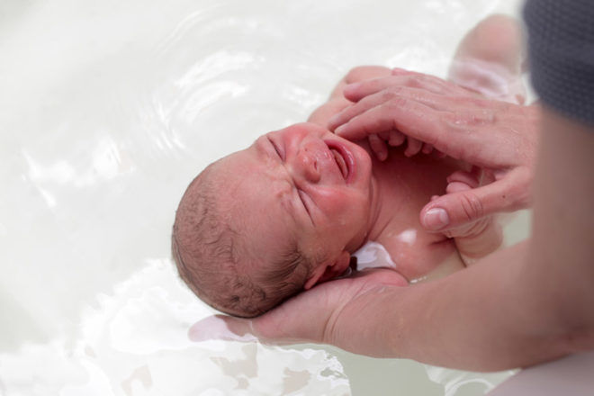 Crying newborn baby in the bath