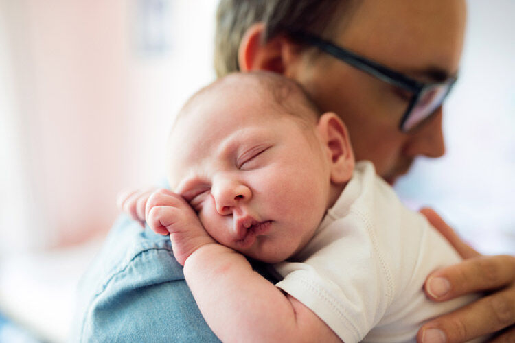 Dad cuddling a newborn on his shoulder