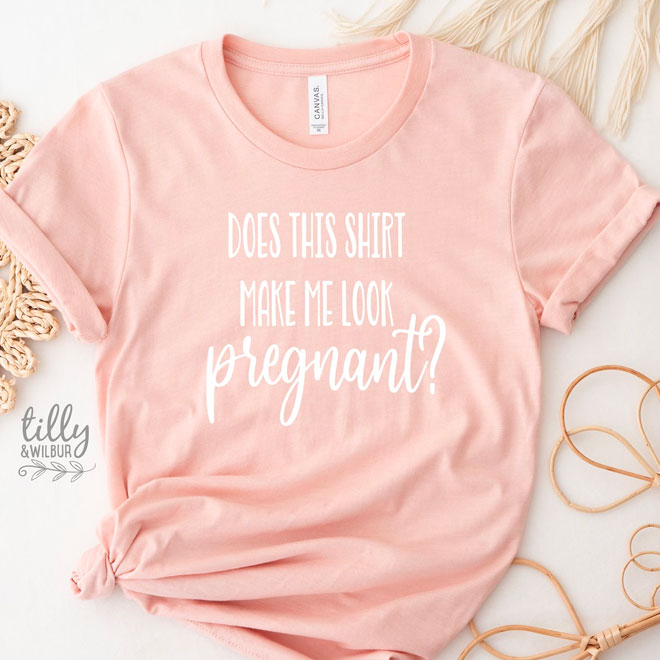 A pink tshirt with the words 'Does this shirt make me look pregnant?' written on the front