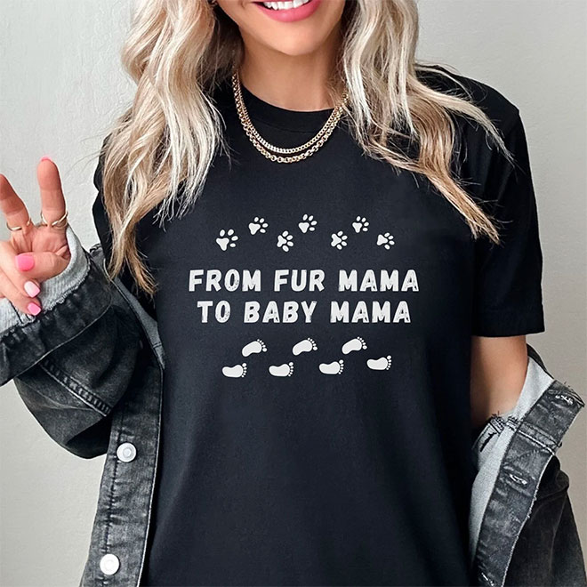 A woman wearing a black t shirt with the words 'From fur Mama to Baby Mama' printed on the front