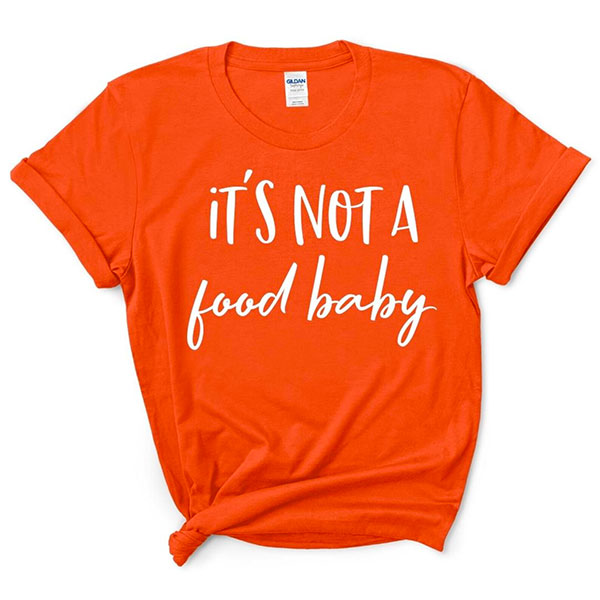 An orange tshirt with the words 'It's not a food baby' written on the front