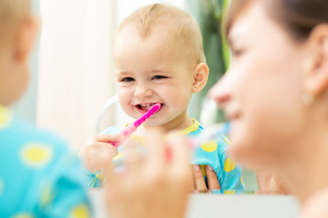 Mother helping child brush their teeth
