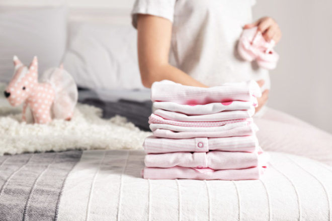 Pregnant woman folding clean baby clothes