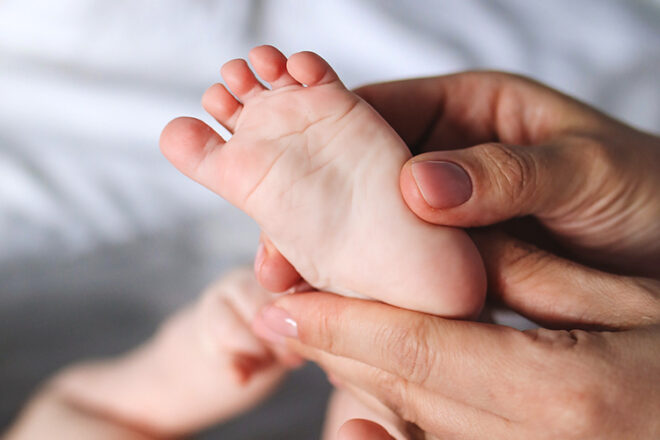 Close up of baby foot showing mother about to massage reflexology points