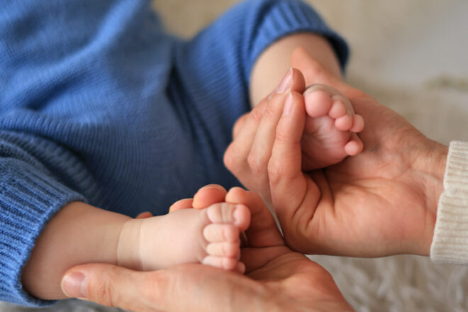 Mother holding infants bare feet after giving foot massage