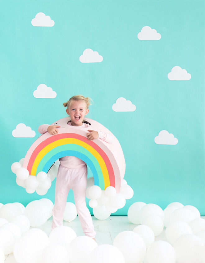 Rainbow Halloween costume suit worn by girl and cloud balloons