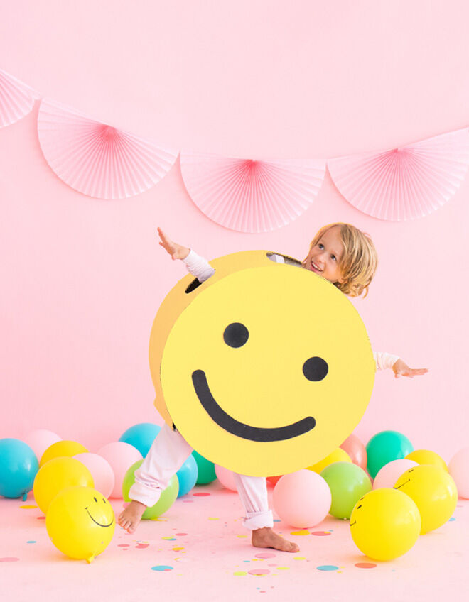 Smiley costume worn by a boy at a party surrounded by balloons