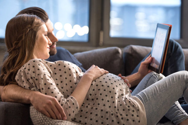 Pregnant woman and partner using tablet