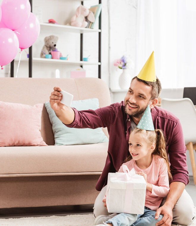 Father and daughter filming unboxing gifts at virtual birthday party