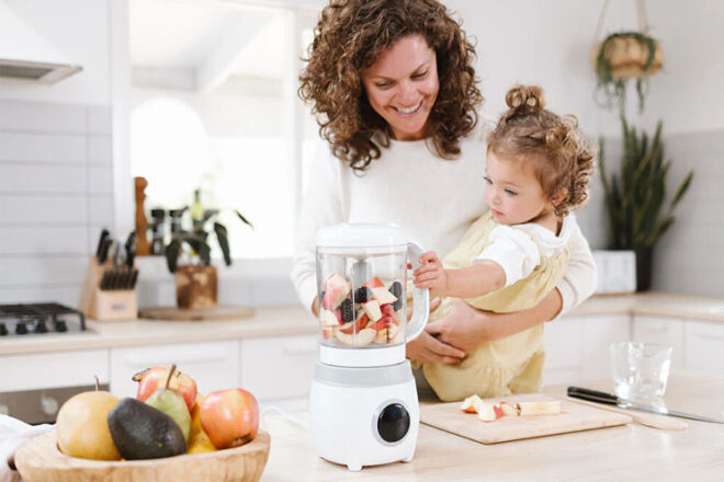 A mother holding her baby using the Cherub Baby Automatic Food Maker