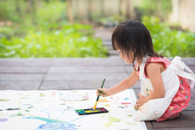 Little girl painting in the garden