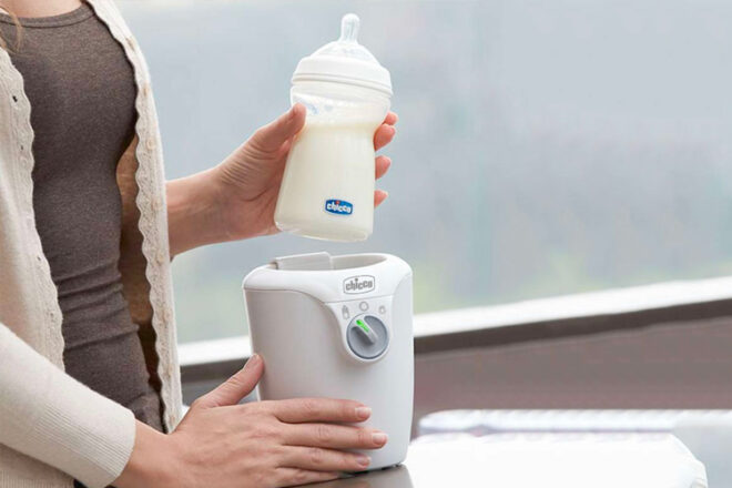 Mother lifing a bottle of warmed milk out of the Chicco Home Electric Bottle Warmer