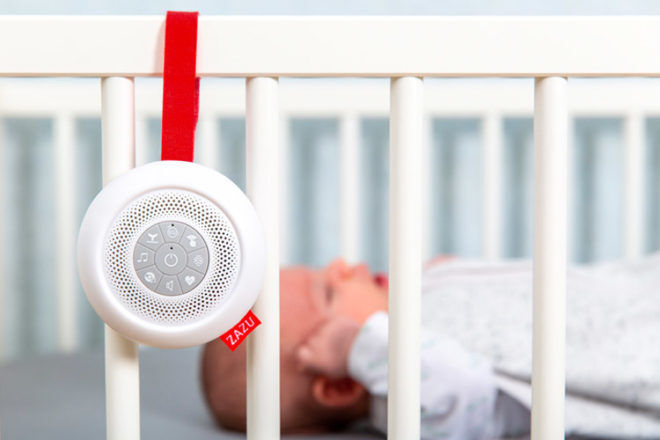 a white noise machine hanging on the side of a babies cot with a baby sleeping inside