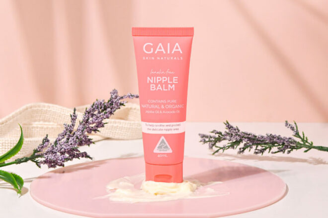 GAIA Nipple Balm sitting in front of a pink background surrounded by lavendar