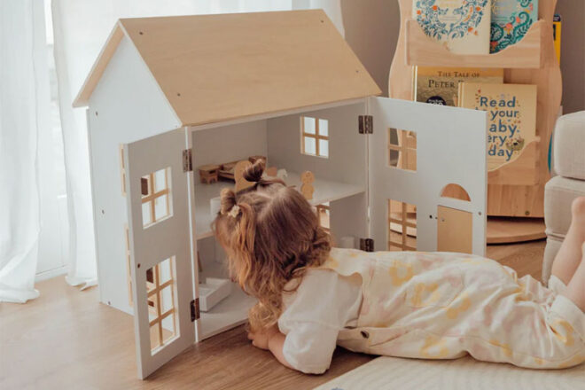 A little girl playing with the ELSA Doll House with Furniture & Doll Family Set from HipKids