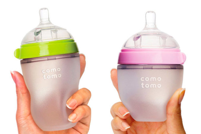 Comotomo Baby Bottles being held in the hand showing the bottles are soft to touch and the wide neck for easy filling with formula