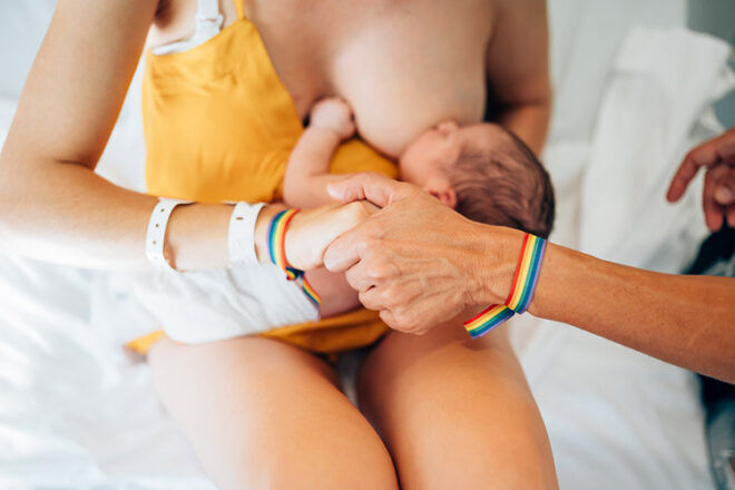 Breastfeeding mum with newborn sitting on bed in hospital breastfeeding a newborn