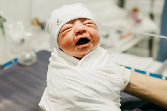 Newborn baby wrapped in swaddle and hat