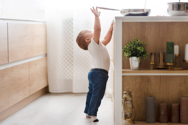 Home safety and babyproofing - Child reaching for hot pot on stove STK