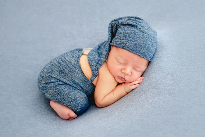 Newborn baby asleep in blue hat and warp