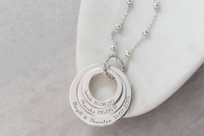 Close up front view of Silvery name necklace showing three rings combined and engraved with important names and dates.